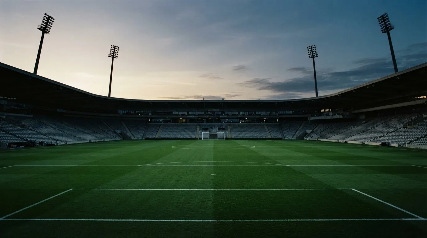 An empty football stadium with floodlight masts at dusk