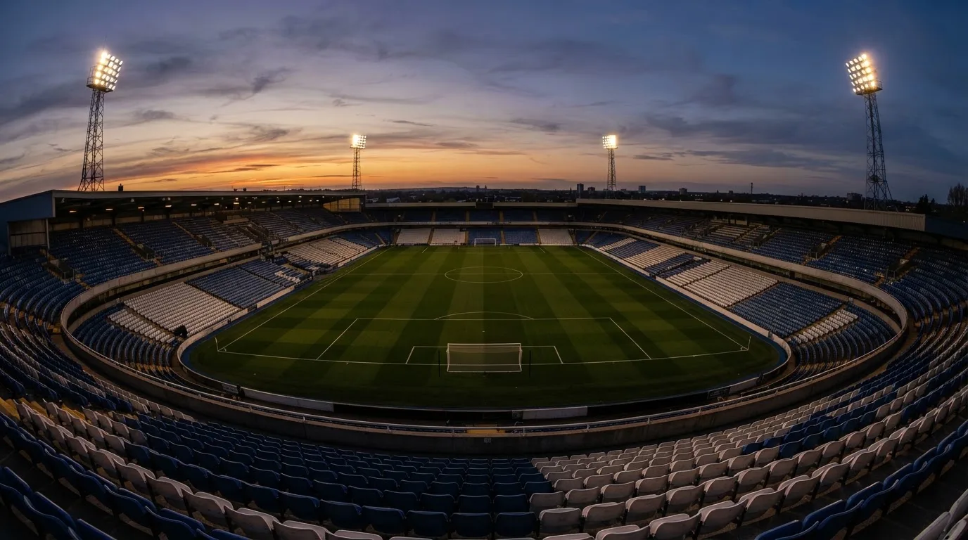 An empty football stadium with floodlight masts at dusk