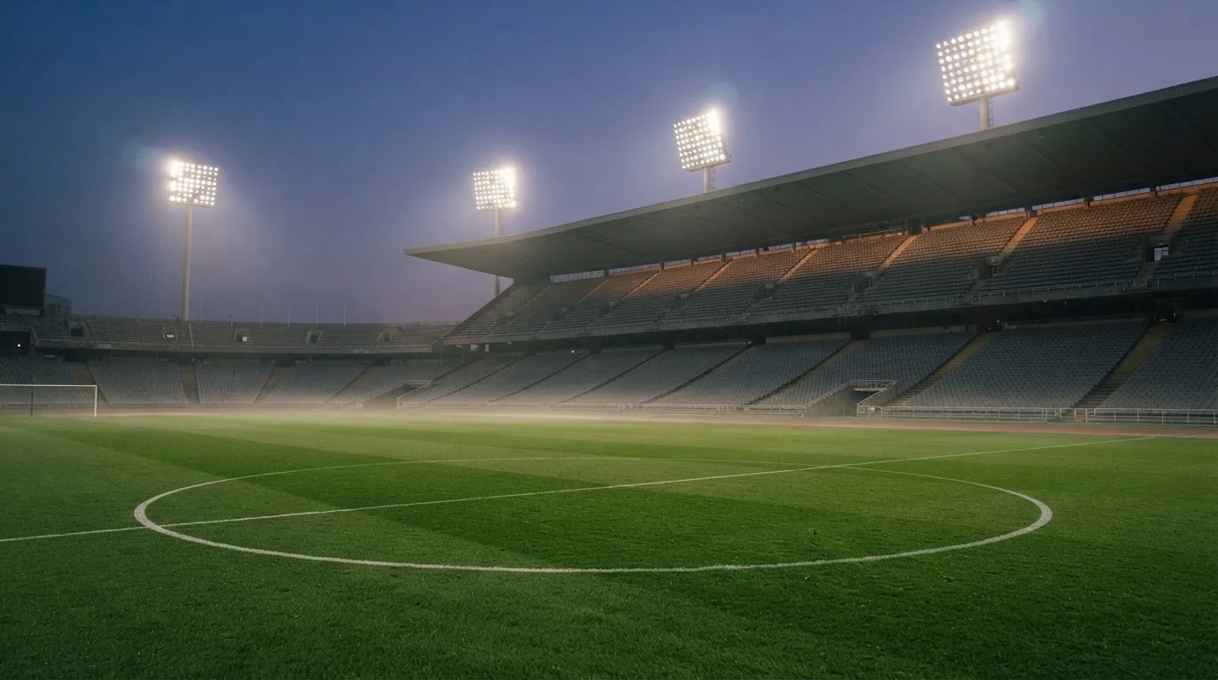 An empty football stadium with floodlight masts at dusk