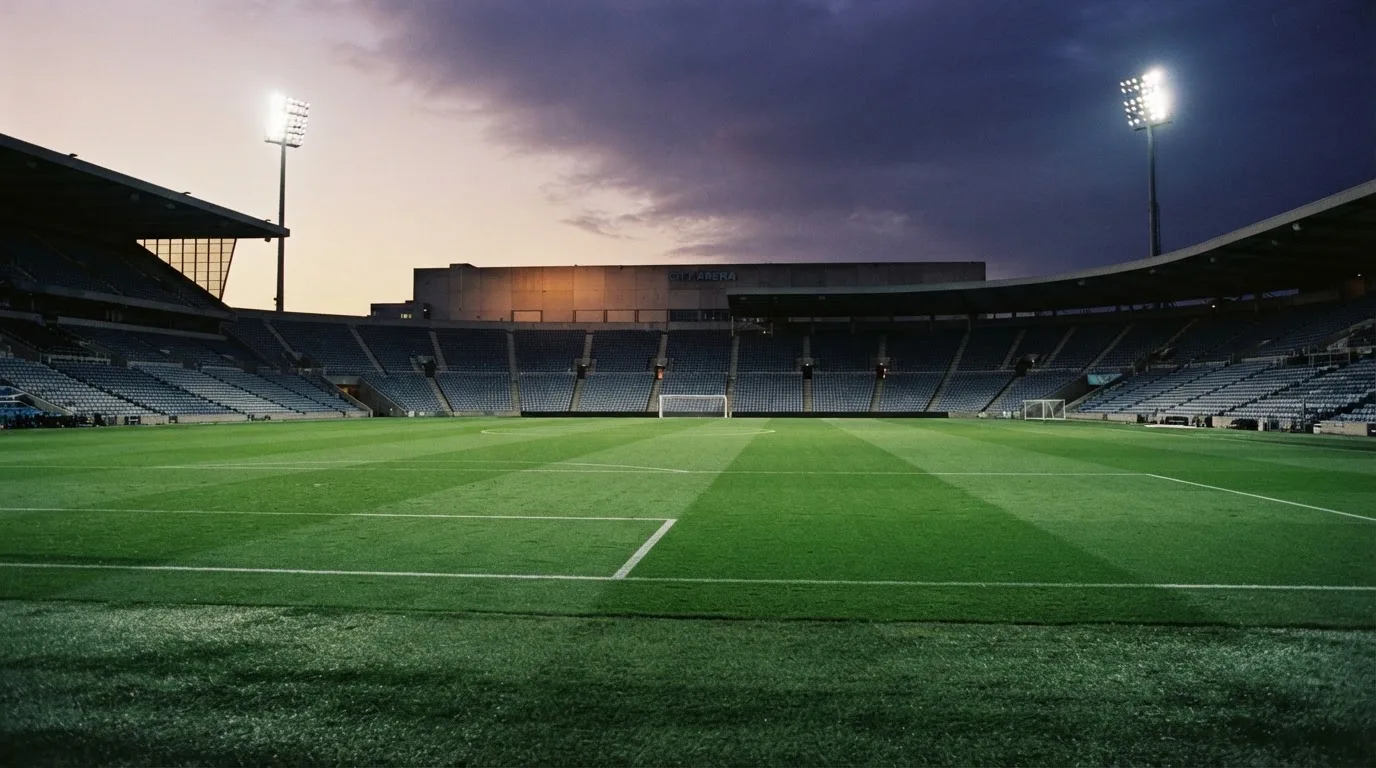 An empty football stadium with floodlight masts at dusk
