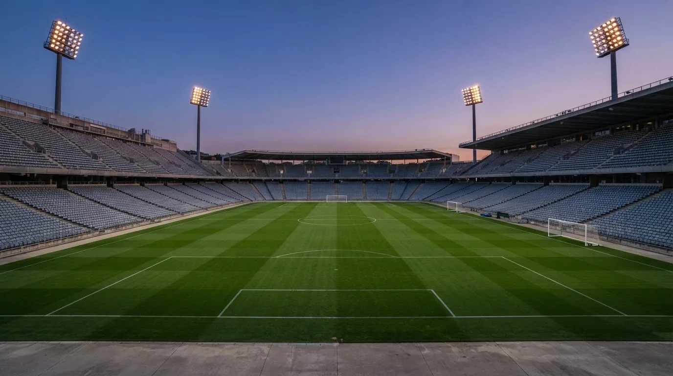 An empty football stadium with floodlight masts at dusk