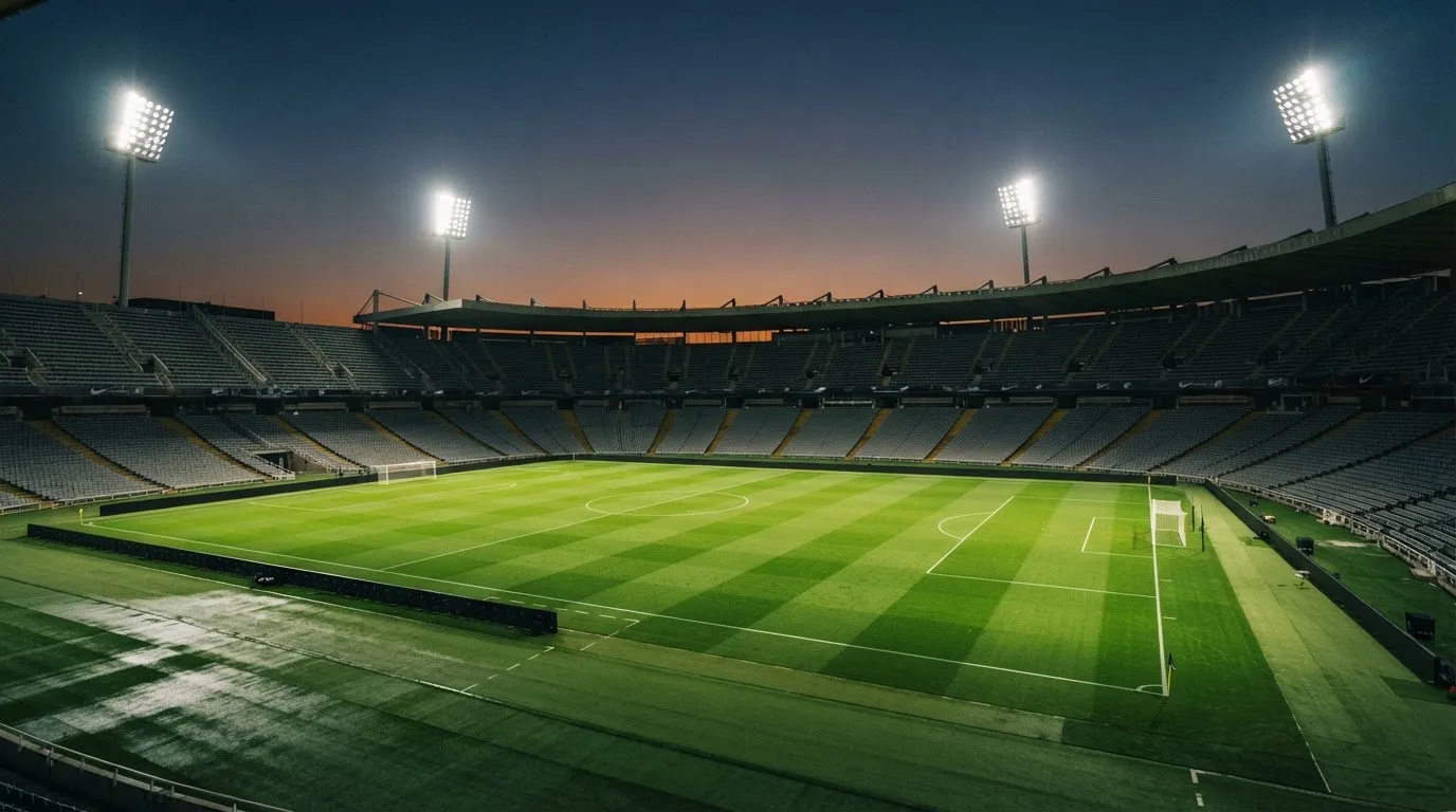 An empty football stadium with floodlight masts at dusk