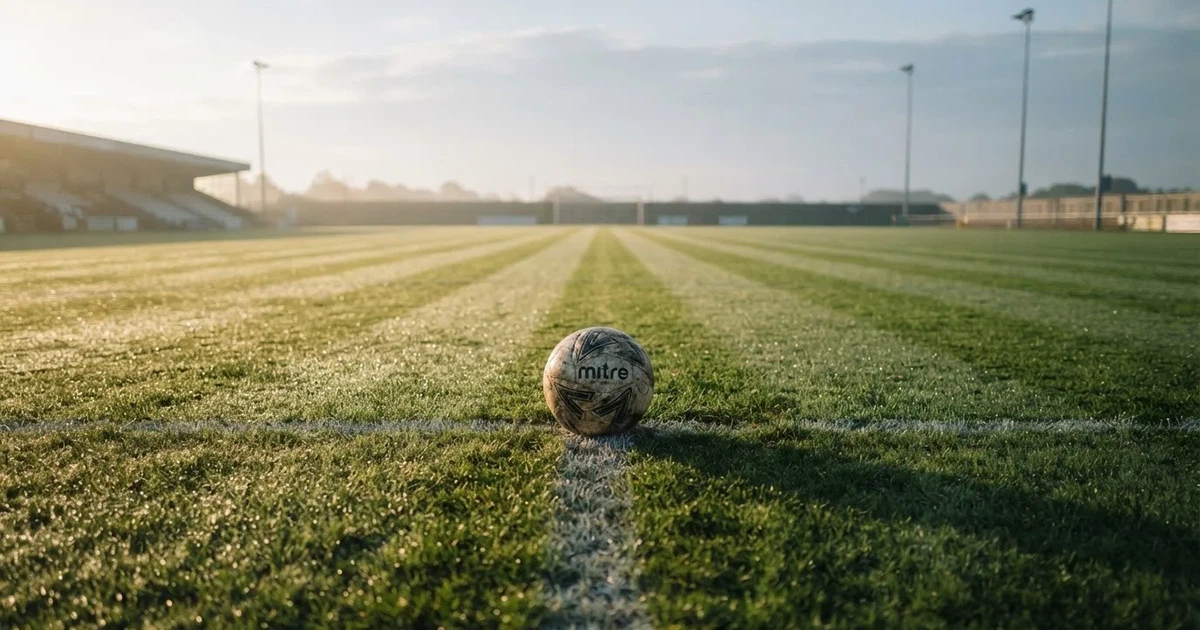 A ball on the centre spot of a grass pitch in morning light