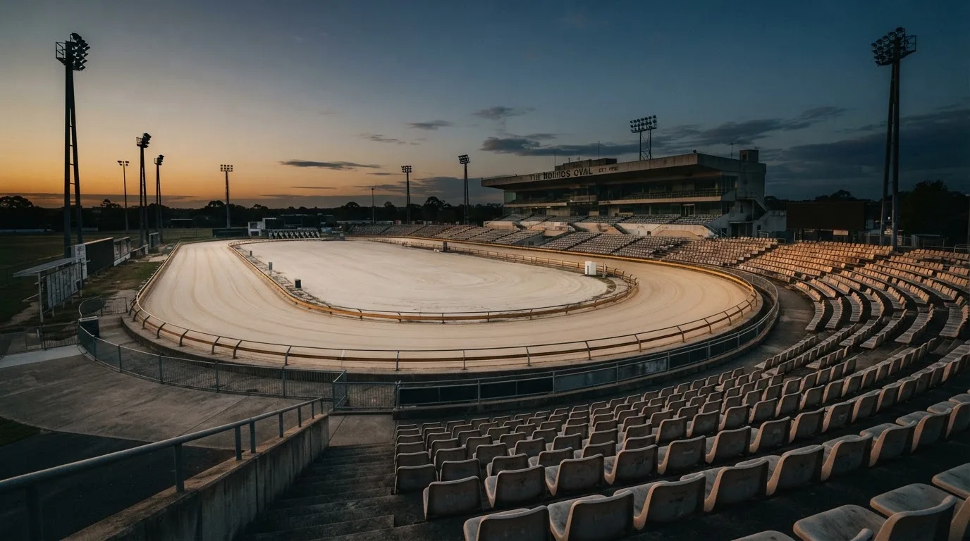 An empty football stadium with floodlight masts at dusk